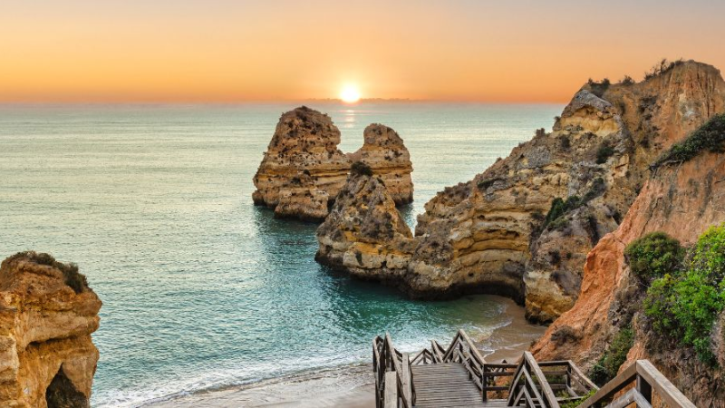 Sandy beach in Portugal with turquoise waves and a clear blue sky.