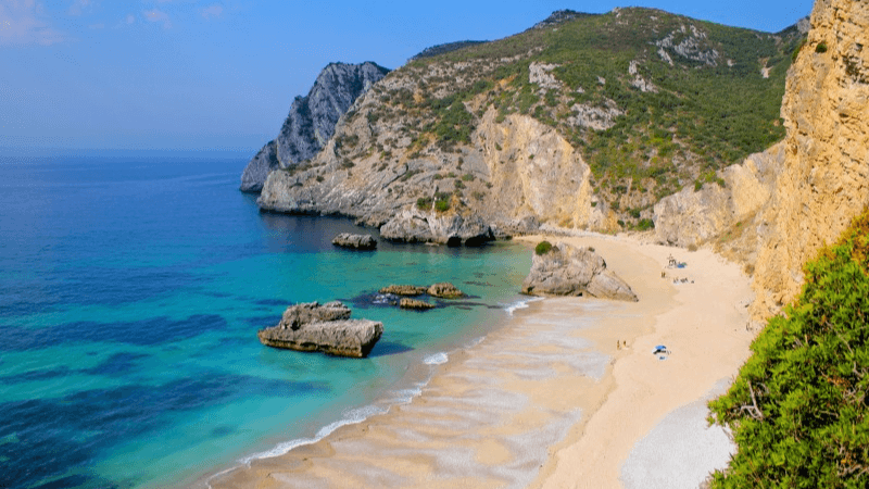 Hidden beach near Lisbon with turquoise waters and dramatic cliffs at Praia da Ribeira do Cavalo in Sesimbra