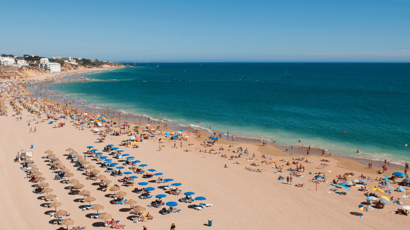 Lively Praia de São João in Costa da Caparica with beach bars, surf, and summer crowds