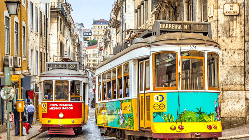 Traditional yellow tram traveling through the streets of Lisbon.
